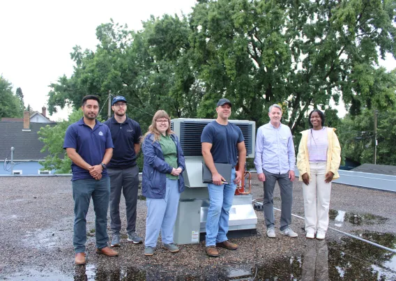 A team of people next to HVAC equipment. 