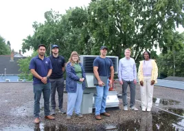 A team of people next to HVAC equipment. 