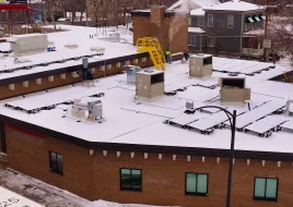 A building with fresh snow and rooftop units. 