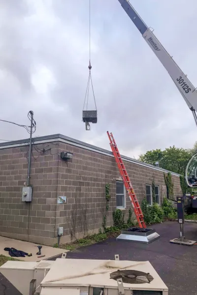 A crane placing a RTU on on top of a building. 